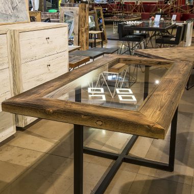 Stół Arles to mebel wykonany ze talowych profili i blatu, który jest połączeniem drewnianej ramy ze szklanym wypełnieniem.